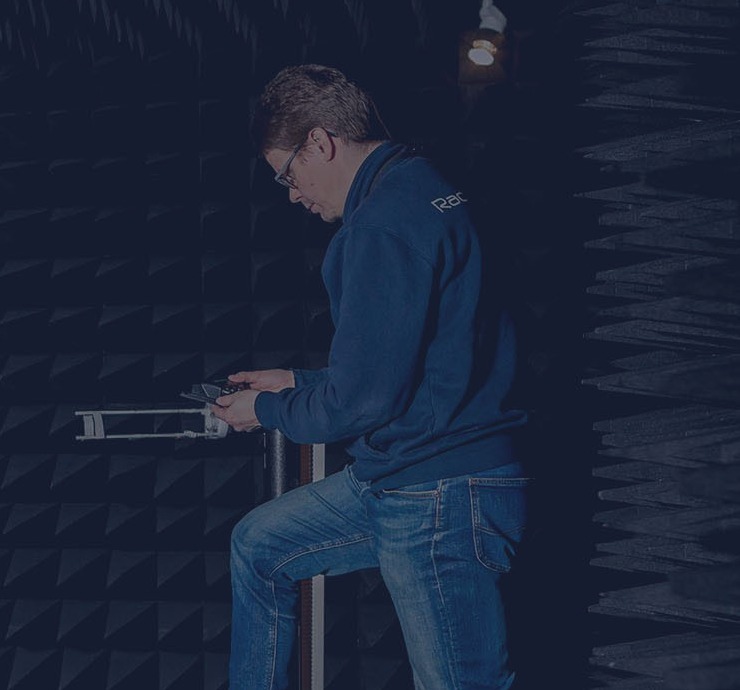 A person standing in anechoic chamber setting up a device for antenna measurement A person standing in anechoic chamber setting up a device for antenna measurement
